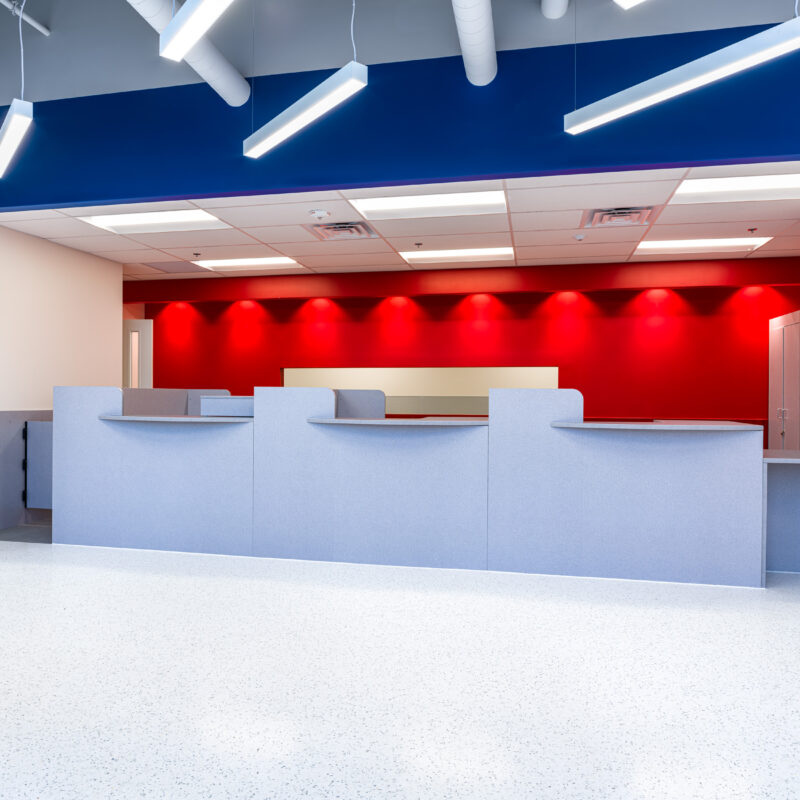 USPS Downtown Las Vegas A sleek, clean lobby area with vibrant red walls behind a stylish front desk, illuminated by modern lighting fixtures. Located at 201 South Las Vegas Blvd.